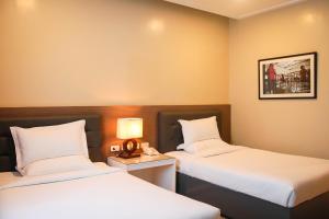 a hotel room with two beds and a lamp at Iloilo Gateway Hotel and Suites in Iloilo City