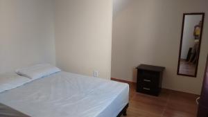 a bedroom with a white bed and a mirror at Casa Costa Azul - praça da Baleia in Rio das Ostras