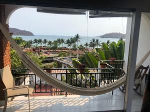 a hammock on a balcony with a view of the ocean at Hotel Villas Ema in Zihuatanejo