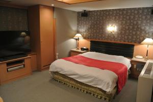 ein Schlafzimmer mit einem großen Bett und einem Flachbild-TV in der Unterkunft アンジェリーククロッシュ 男塾ホテルグループ in Himeji