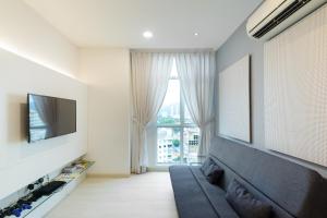 een woonkamer met een bank, een tv en een raam bij Straits Garden Suites, Georgetown in George Town