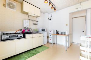 a kitchen with white cabinets and a green rug at Kappo INN Tokusa in Hashimoto