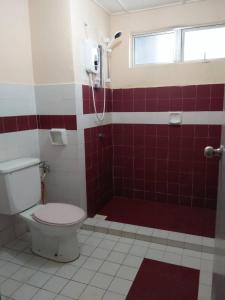une salle de bain rouge et blanche avec toilettes et douche dans l'établissement Marina View, Teluk Kemang, PD, à Port Dickson