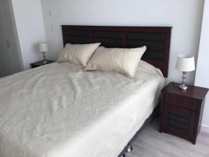 1 dormitorio con 1 cama blanca grande y 2 mesitas de noche en Moderno y funcional departamento Miraflorino, en Lima