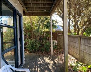 a porch with a white chair on a patio at Wrights by the Sea Motel in Paraparaumu Beach