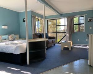 a bedroom with blue walls and a bed and a couch at Wrights by the Sea Motel in Paraparaumu Beach