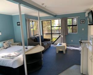 a hotel room with a bed and a couch and windows at Wrights by the Sea Motel in Paraparaumu Beach