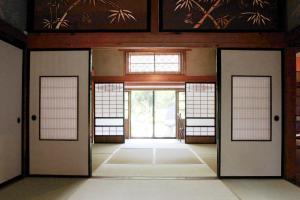 an empty room with doors and windows in a building at carafuru Japanese Old House in Sado