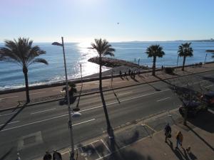 a view of a street with palm trees and the ocean at Hôtel du Bord de Mer "Le Vanillé" in Cagnes-sur-Mer