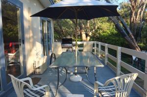 Beachwalk Cottage في سورينتو: طاولة وكراسي على شرفة مع مظلة