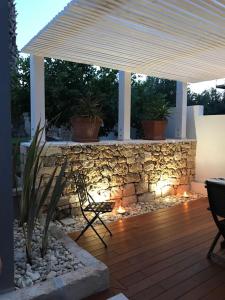 patio con parete in pietra e ombrellone bianco di Campo Reale country rooms a Pachino