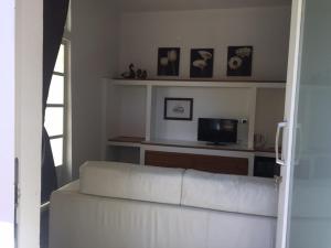 a living room with a white couch and a tv at Campo Reale country rooms in Pachino