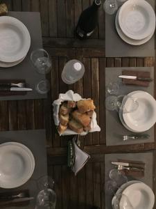 un tavolo con piatti e bicchieri bianchi e un cesto di cibo di Campo Reale country rooms a Pachino