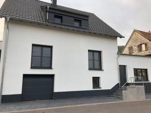 a white house with black windows and a garage at Ferienwohnung Kirschholz in Schmelz