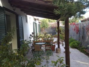 patio con tavolo e sedie sotto un pergolato di Villa Verdemare Naxos a Giardini Naxos
