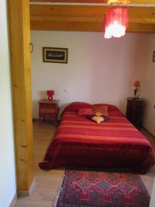 1 dormitorio con 1 cama grande con colcha roja en Gite les Camélias, en Sainte-Anne-sur-Vilaine