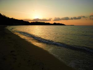 a sunset on a beach with the ocean at Miyuki Hamabaru Resort in Onna