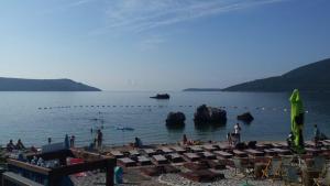 a beach with a bunch of chairs and people on it at Apartments Astoria HN in Herceg-Novi