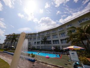 a large building with a swimming pool and a fountain at Miyuki Hamabaru Resort in Onna