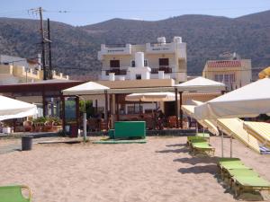 a beach with chairs and umbrellas in front of a building at Smaragdine Beach Hotel in Stalís