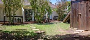 a backyard with a wooden fence and grass and trees at Crowned Crane in Gonubie