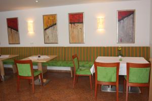 un restaurante con mesas, sillas y pinturas en la pared en Hotel Sonnenhof, en Timelkam