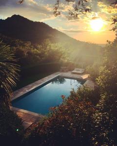 uma piscina num jardim com o pôr-do-sol em Le Mouron Rouge em La Garde-Freinet
