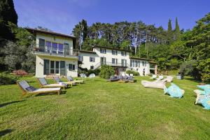 une grande cour avec des chaises longues et une maison dans l'établissement Tenuta La Pineta, à Salò