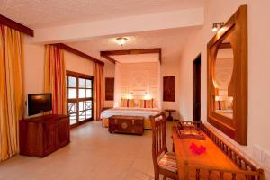 una camera d'albergo con letto e TV di Neptune Village Beach Resort & Spa - All Inclusive a Galu