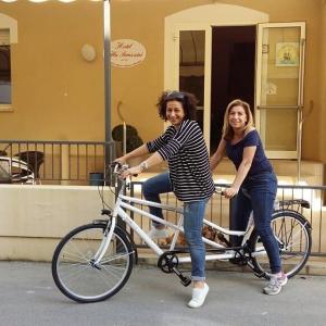 Due donne stanno andando in bicicletta per strada di Hotel Villa Perazzini a Rimini