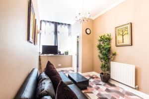 een woonkamer met een leren bank en een tv bij Montgomery Apartments - Crighton in Edinburgh