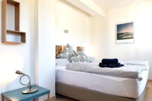 a white bedroom with a bed and a blue table at Ferienwohnung "Solopgang" im Haus Granitz in Binz