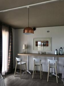 a kitchen with a bar with three chairs and a light fixture at B&B Bellavista in Tavullia