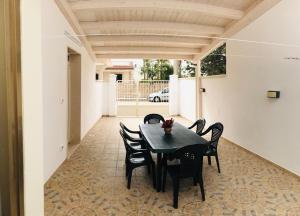 a dining room with a black table and chairs at Villetta Natalia in Torre Colimena