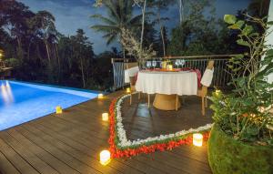 a dining table on a deck next to a pool at River Sakti Ubud by Prasi in Ubud