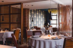 a restaurant with white tables and chairs and windows at The Club Hotel & Spa Jersey in Saint Helier Jersey