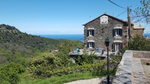 English Club in Corsica A في Porri: منزل حجري على تلة مع المحيط في الخلفية