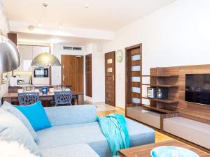 salon z niebieską kanapą i kuchnią w obiekcie VacationClub – Olympic Park Apartament A412 w Kołobrzegu