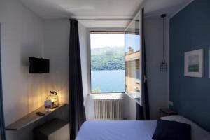 a bedroom with a window with a view of the water at Hotel Orso Bruno in Carate Urio