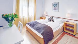ein Schlafzimmer mit einem Bett und einem Tisch mit einer Vase in der Unterkunft Hotel Cornelia in Bad Nauheim