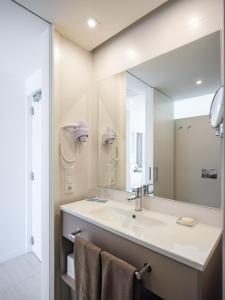 een badkamer met een wastafel en een grote spiegel bij Son Matias Beach - Adults Only in Palmanova