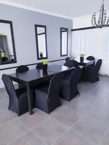 comedor con mesa negra y sillas en Hiflyerz Guest House, en Boksburg