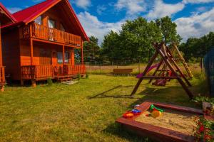 a log cabin with a sandbox and a playground at Domki Zacisze in Ostrowo