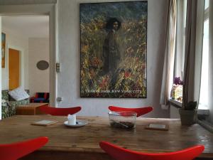 a dining room table with red chairs and a painting on the wall at Cosy Farmhouse Single bedroom in Stege