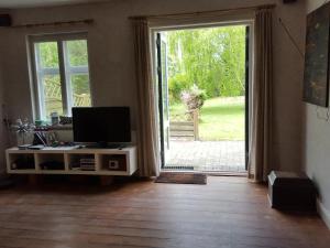 a living room with a television and a sliding glass door at Cosy Farmhouse Single bedroom in Stege