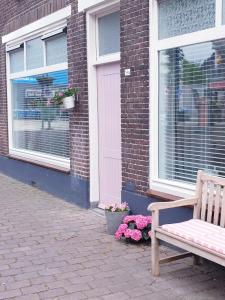 a bench sitting in front of a building with flowers at Appartement Plek in Holten in Holten