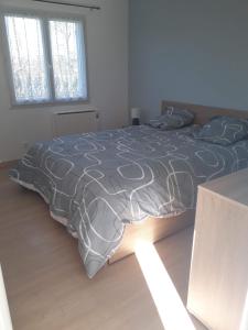 a bedroom with a bed with a gray and white comforter at Ferme en pleine campagne in Castelsagrat