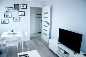 a white living room with a tv and a table at Apartament Wiesio in Gdynia