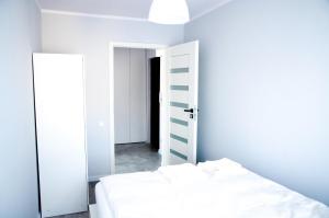 a bedroom with a white bed and a mirror at Apartament Wiesio in Gdynia