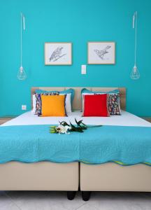 een blauwe slaapkamer met een groot bed met kleurrijke kussens bij Yiannis Studios in Agia Marina Aegina